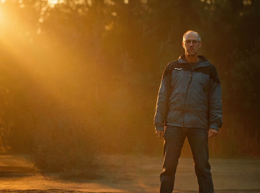 The same man in glasses, relit in warm golden-hour sunlight